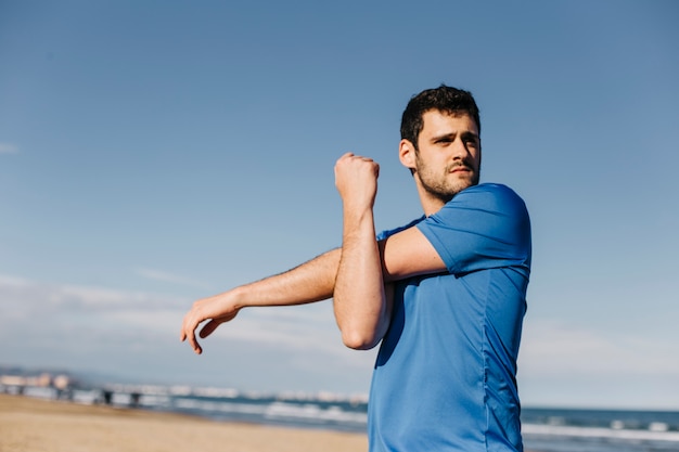 Foto man die zich uitstrekt op het strand