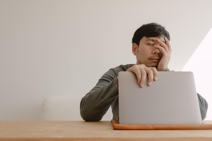 Man die zich verveelt, moe en slaperig voelt bij het werken met de computer