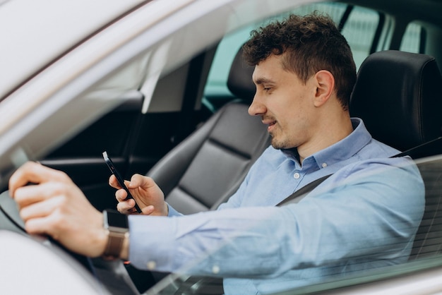 Man die zijn auto bestuurt en mobiele telefoon gebruikt