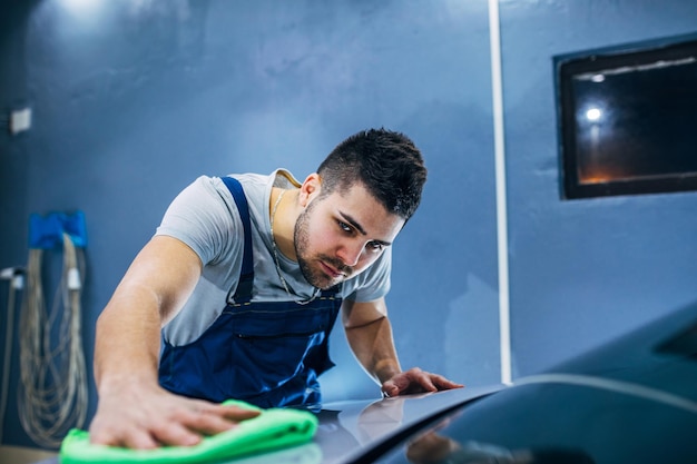 Man die zijn auto schoonmaakt in een werkplaats