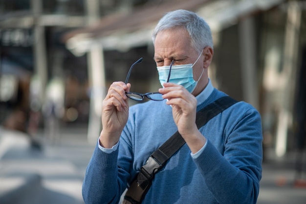 Man die zijn bril schoonmaakt, beslagen vanwege het masker covid coronavirus visie concept