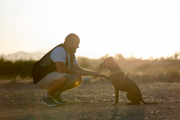 Man die zijn hond buiten traint bij zonsondergang