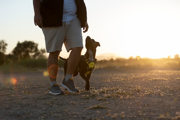 Foto man die zijn hond buiten traint bij zonsondergang