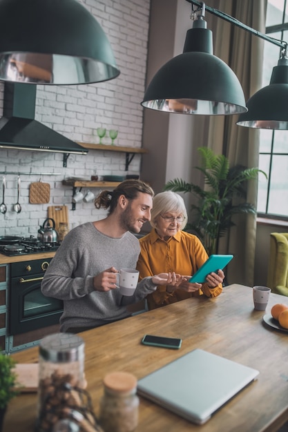 Man die zijn moeder laat zien hoe hij de tablet moet gebruiken