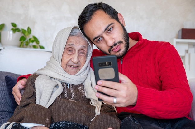 Foto man die zijn smartphone toont aan zijn islamitische grootmoeder