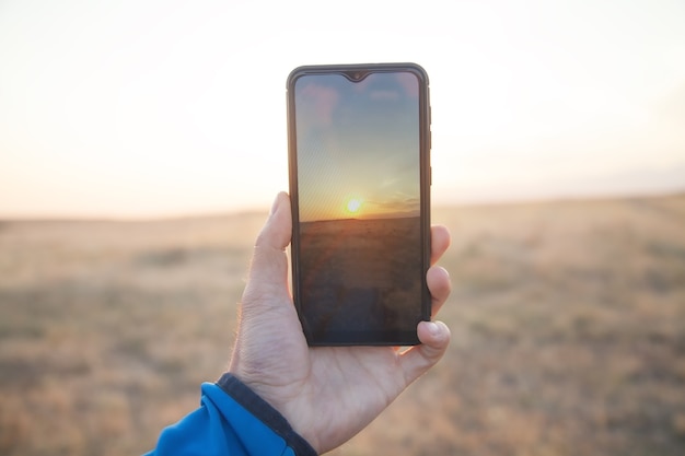 Man die zonsondergang met zijn smartphone.