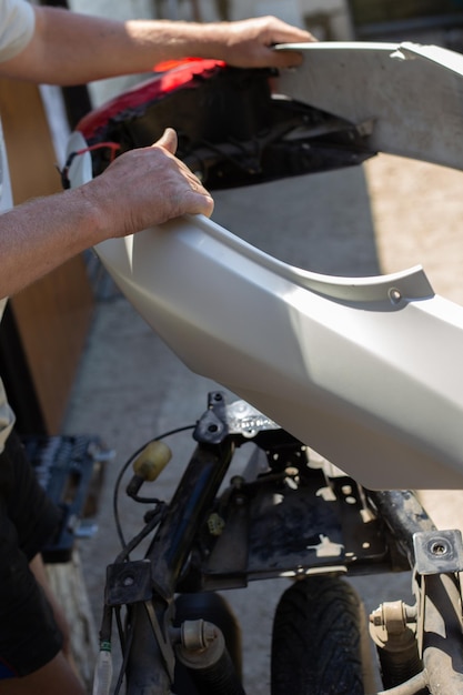 A man disassembles a motorcycle for repair removes the body kit of a motorbike