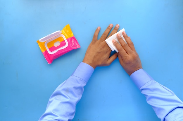 Photo man disinfecting his hands with a wet wipe on blue background