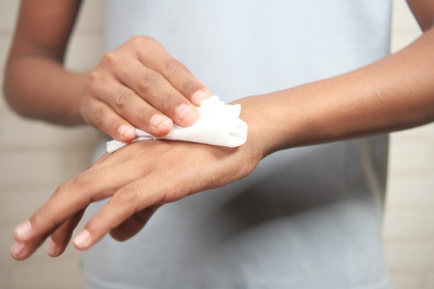 man disinfecting his hands with a wet wipe