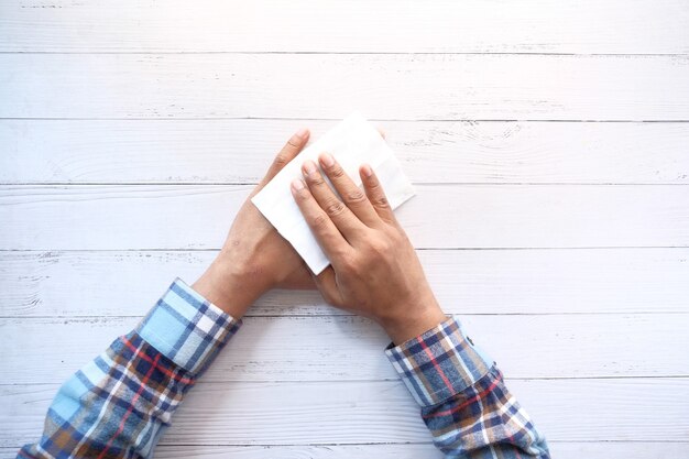 Man disinfecting his hands with a wet wipe.