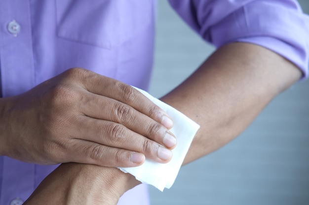 man disinfecting his hands with a wet wipe
