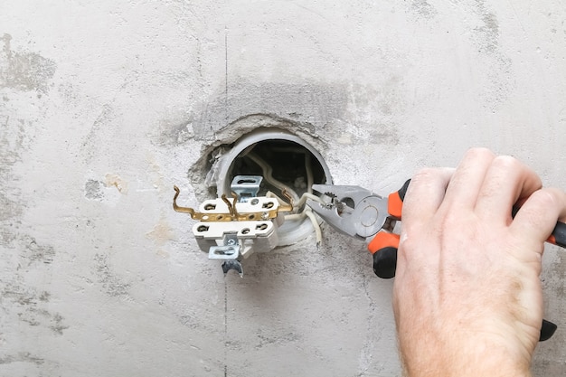 Man dismantles and mends an electrical outlet for repairs