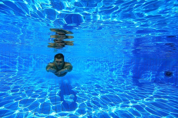 man dives into the pool underwater photo