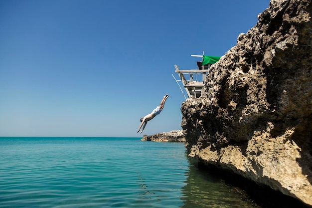 Мужчина ныряет в море со скалы Италия Отдых на Адриатическом море