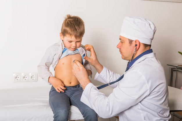 Man doctor and child patient.  Male pediatrician with stethoscope listening to lung and heart sound of little boy