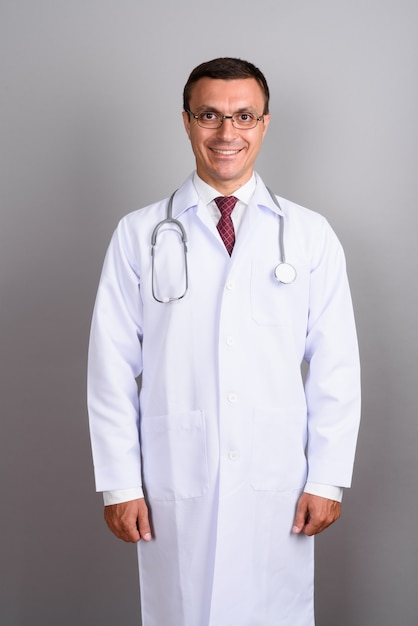 Man doctor wearing eyeglasses against gray wall