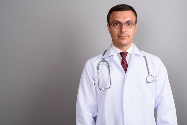 Man doctor wearing eyeglasses against gray wall