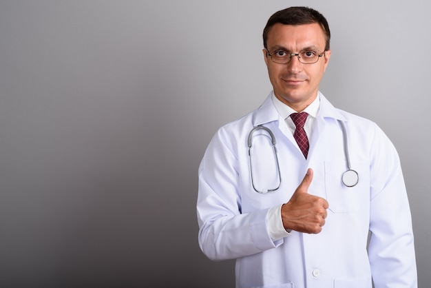 Man doctor wearing eyeglasses against gray wall