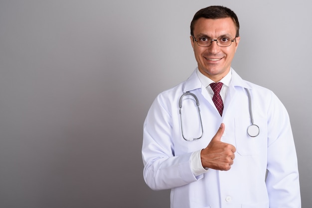 Man doctor wearing eyeglasses against gray wall