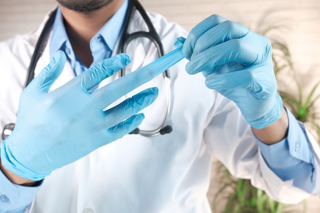 man doctor wears medical gloves, close up