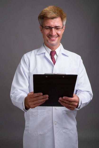 Man doctor with blond hair against gray wall