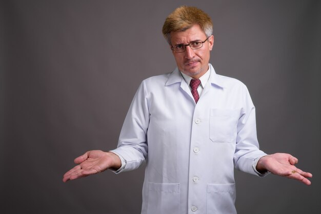 Man doctor with blond hair against gray wall