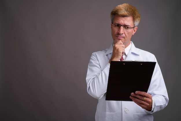 Man doctor with blond hair against gray wall