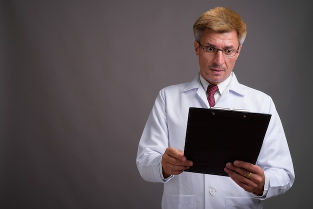 Man doctor with blond hair against gray wall