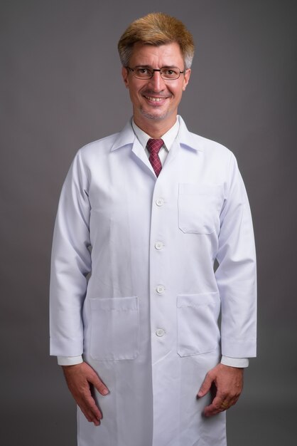 Man doctor with blond hair against gray wall