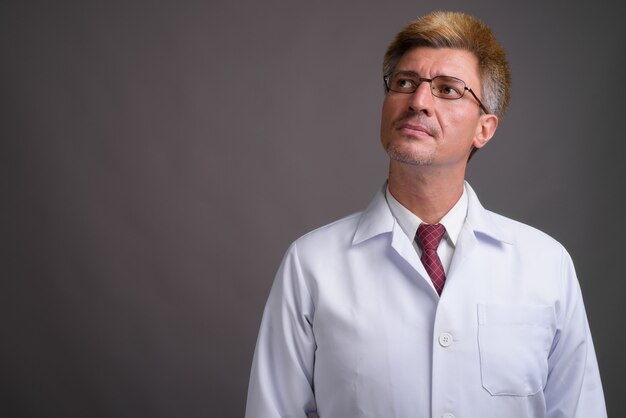 Man doctor with blond hair against gray wall