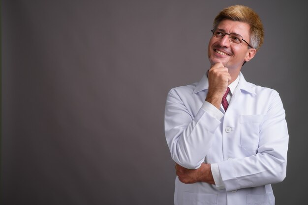 Man doctor with blond hair against gray wall