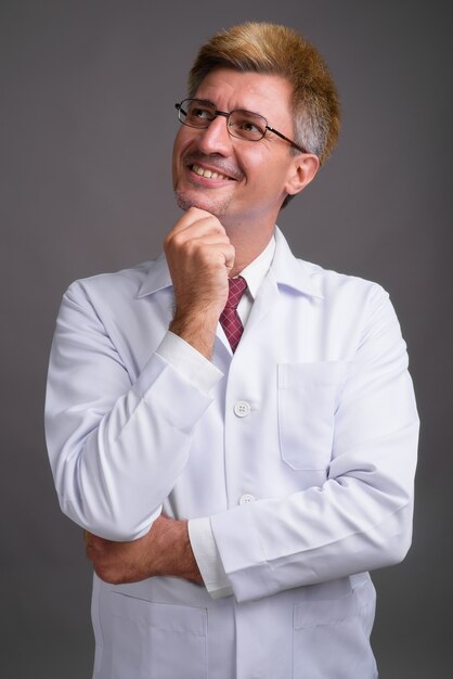 Man doctor with blond hair against gray wall