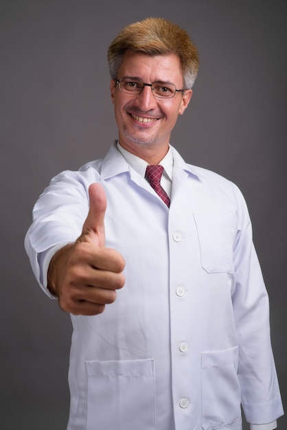 Man doctor with blond hair against gray wall