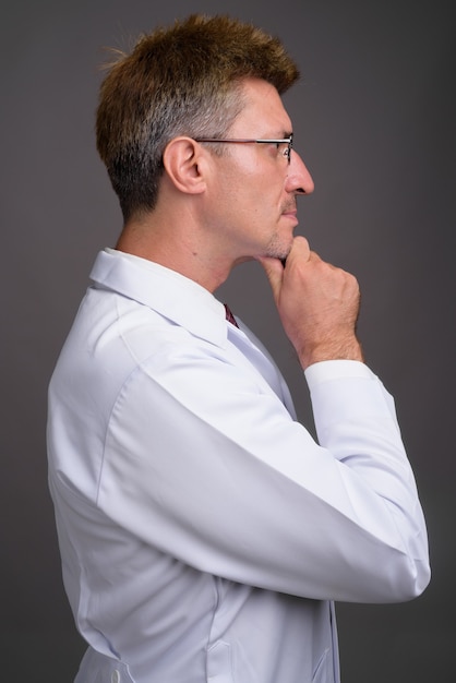 Man doctor with blond hair against gray wall