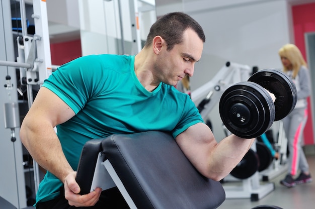 Man doet biceps oefening op scott bench met dumbbell