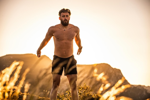 Man doet conditietraining op de top van een berg in de vroege ochtend met de zonsopgang op de achtergrond