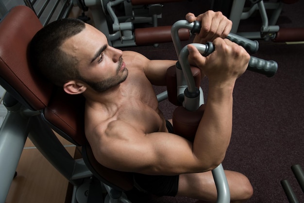 Man doet fitnesstraining op een vlindermachine met gewichten in een sportschool