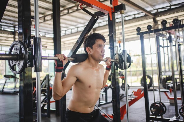 Foto man doet squat oefeningen met een barbell in de sportschool