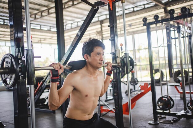 Foto man doet squat oefeningen met een barbell in de sportschool