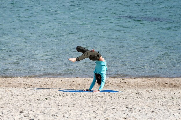 Man doet yoga aan de kust