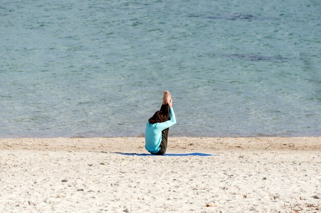 Man doet yoga aan de kust