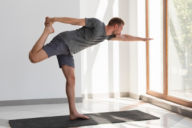 Foto man doet yoga binnen kijken door raam