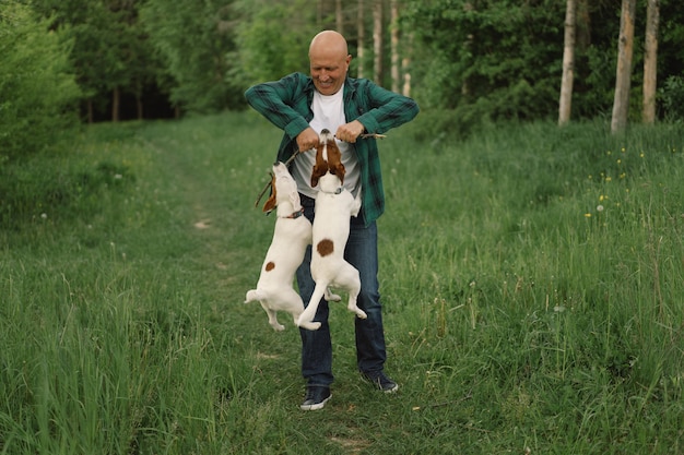 男と犬の友情。男は牧草地でジャックラッセルテリア犬を演じます。