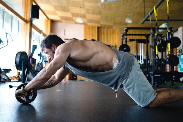 Uomo che fa addominali con una ruota in palestra