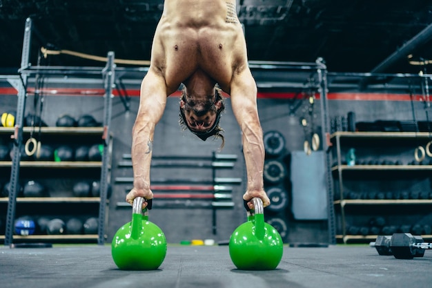 Man doing acrobatics with kettlebells in a gym