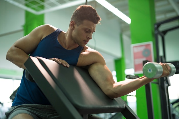 The man doing biceps exercise with a dumbbell