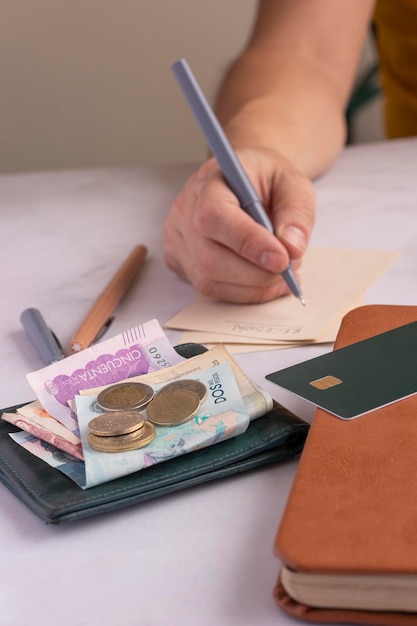 Man doing budget plans with pen and paper and Colombian money