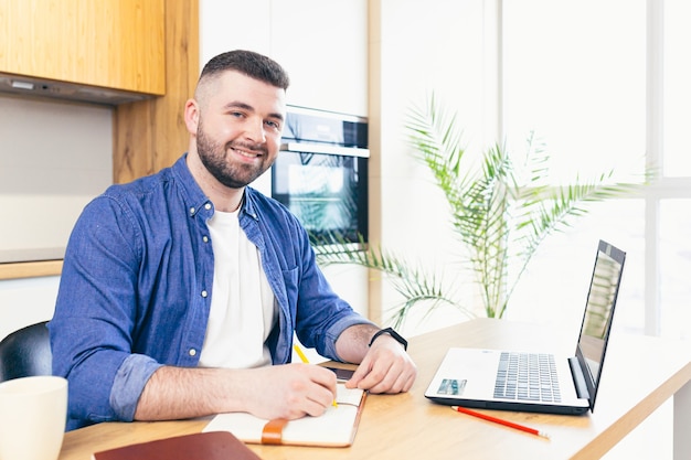 man doing business while staying at home sitting in the kitchen at the table and using a laptop