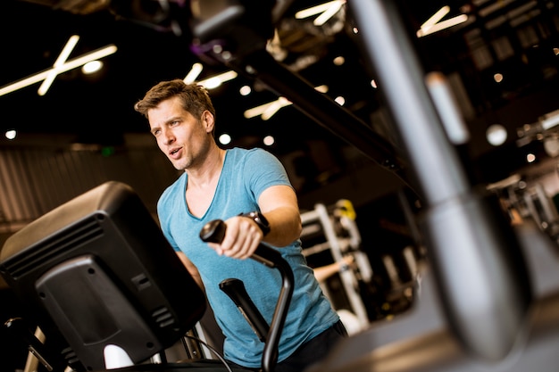 Фото Человек делает упражнения на эллиптический тренажер в спортивном фитнес-клубе