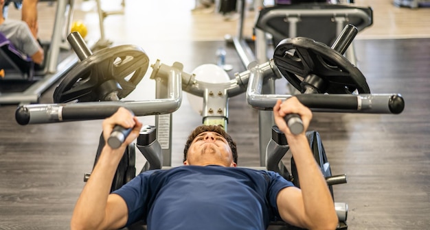 Foto un uomo che fa esercizi su una macchina in palestra